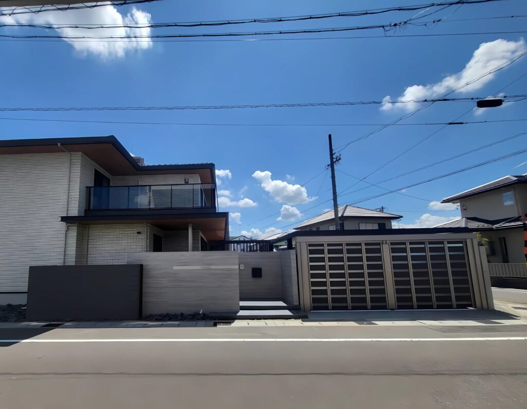 2階建て住宅の外構全景。塀と門まわり、シャッターゲート付きの駐車スペース
